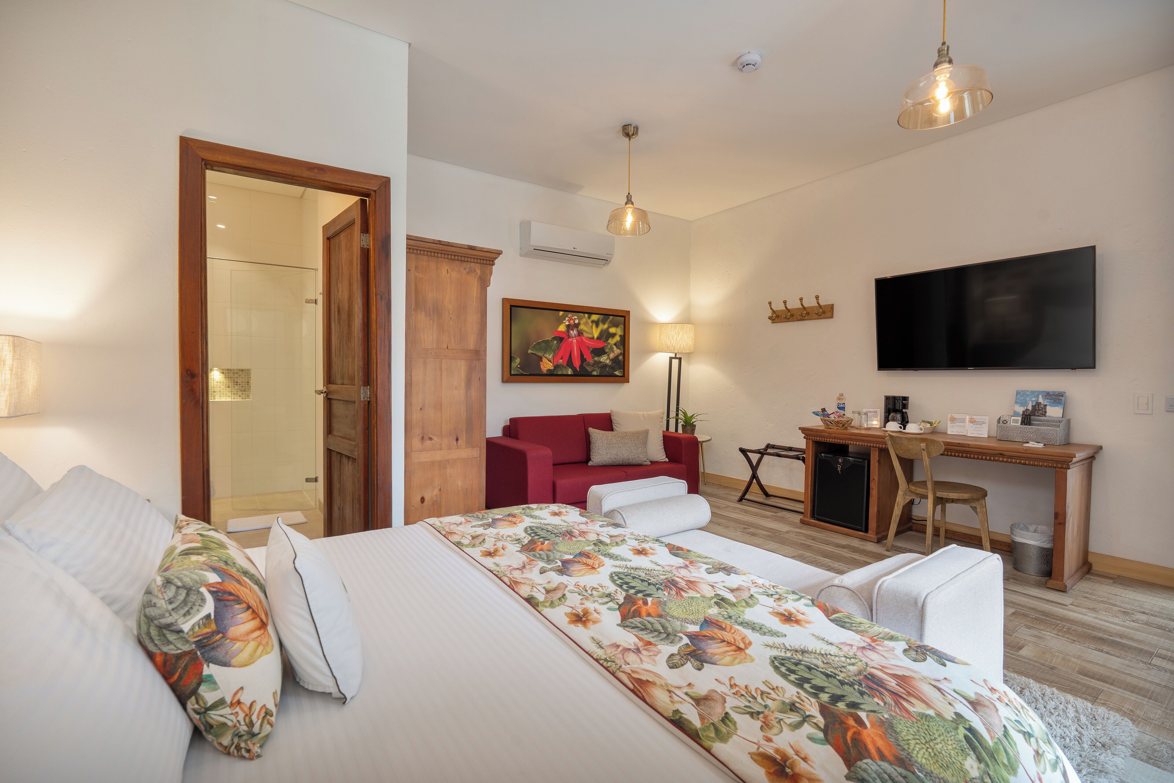 Un dormitorio con cama, escritorio, silla, televisor y puerta que da a un baño.