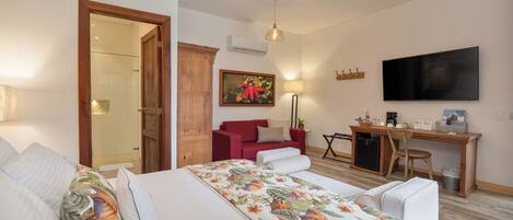 Un dormitorio con cama, escritorio, silla, televisor y puerta que da a un baño.