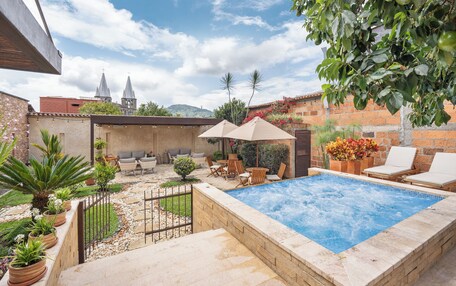 A backyard with a swimming pool, outdoor seating, and a view of a church.