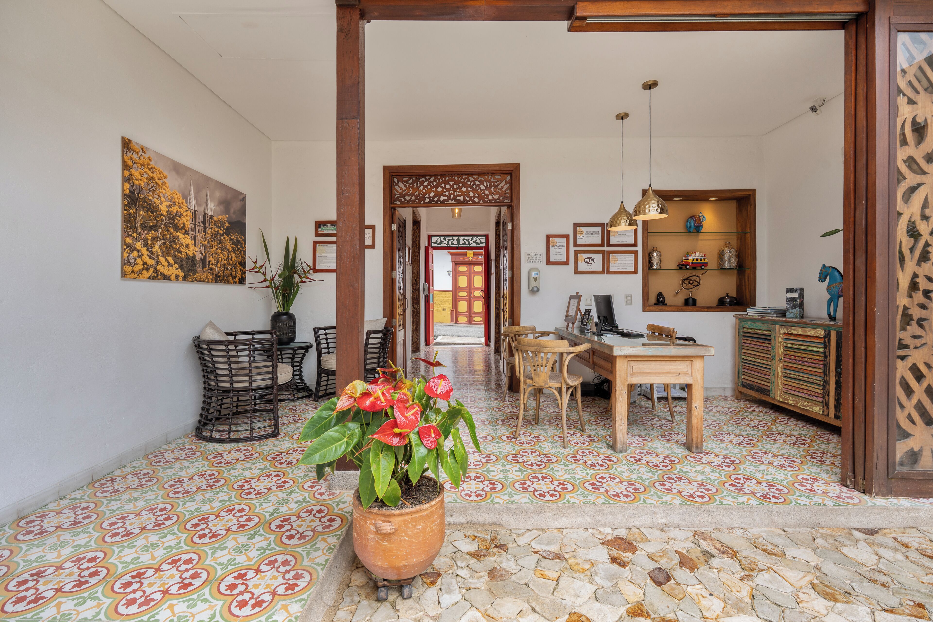 A spacious lobby with a tiled floor, a central potted plant, and a wooden reception desk.