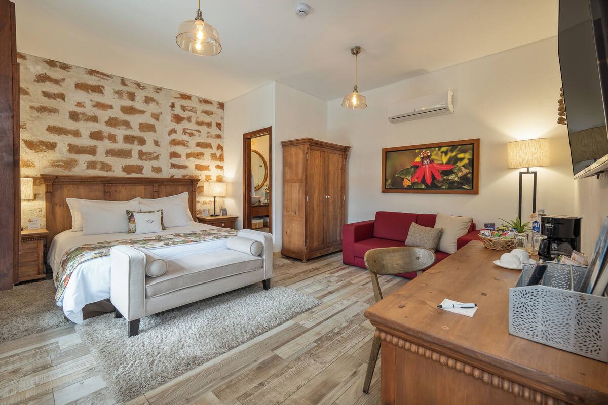 Ein Schlafzimmer mit einem großen Bett, einem Holzschrank, einem roten Sofa und einem Holztisch.