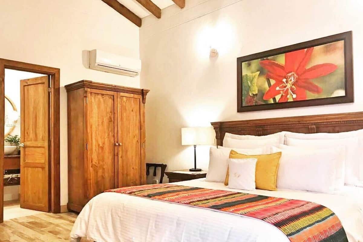 Ein Hotelzimmer mit einem großen Bett, einem Holzschrank und einem Gemälde an der Wand.
