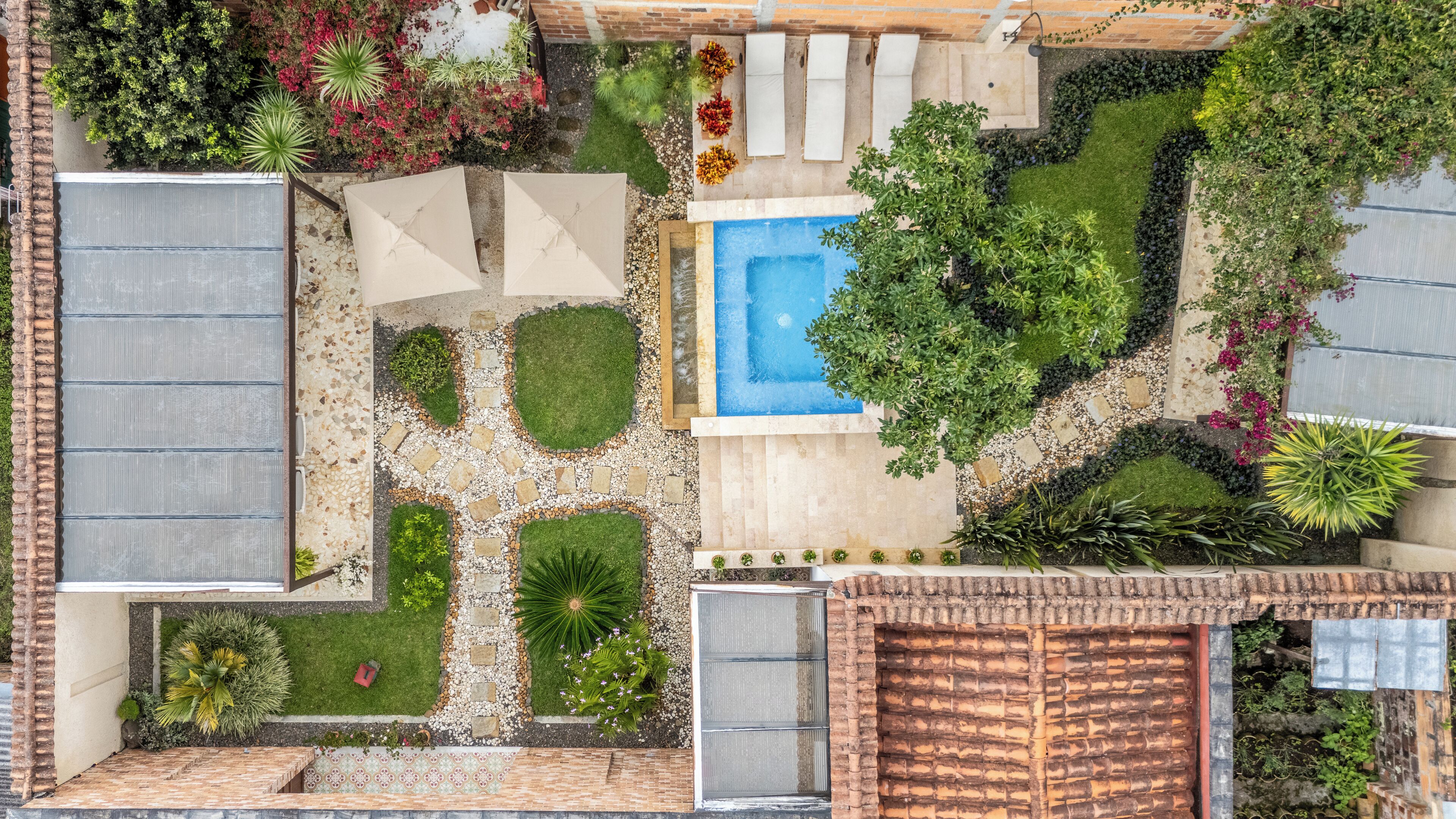 Un jardín en la azotea con piscina, zonas de estar y diversas plantas.