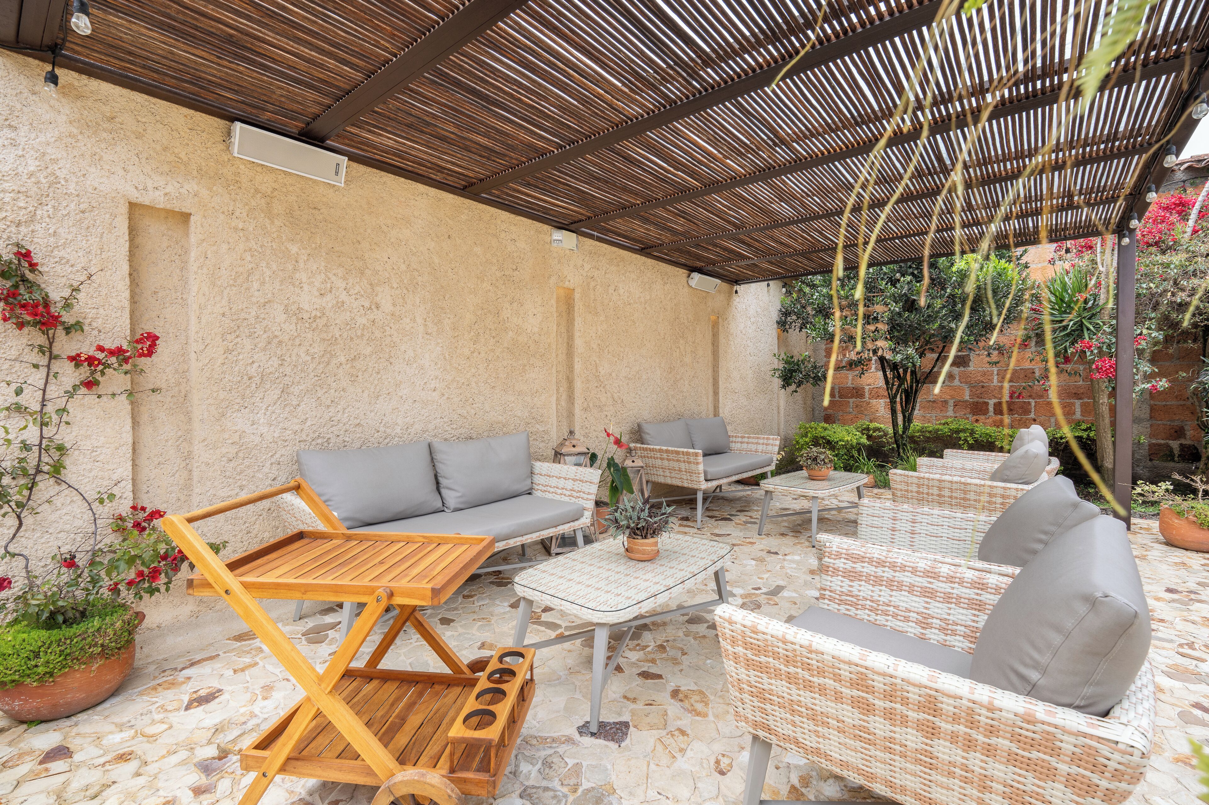 A covered outdoor seating area with wicker furniture and a stone floor.