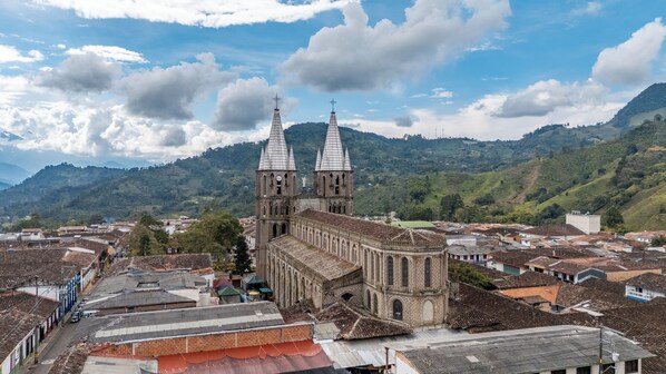Una iglesia histórica con dos torres y un campanario grande, rodeada de edificios tradicionales y colinas verdes exuberantes.