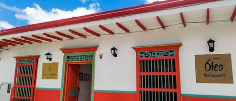 A building with a red and white facade, a red roof, and a sign that reads "Oleo Restaurante".