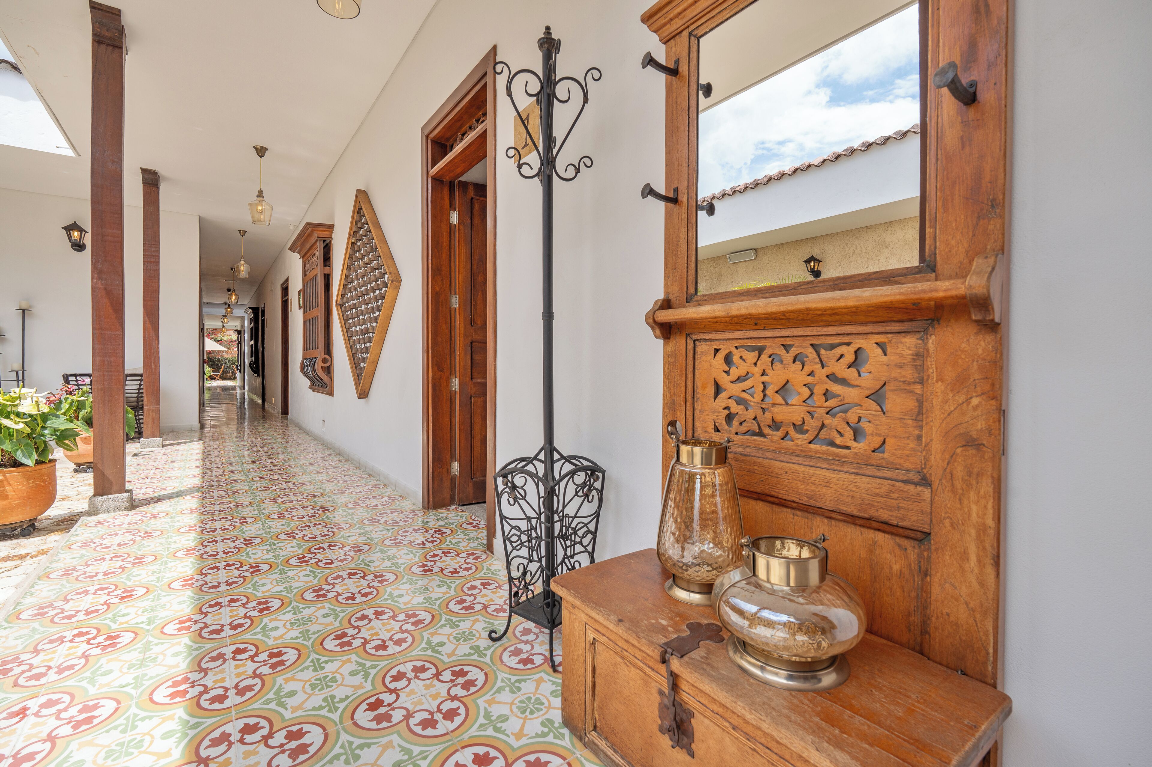 A hallway with patterned floor tiles, wooden doors, and a wooden cabinet with decorative items.