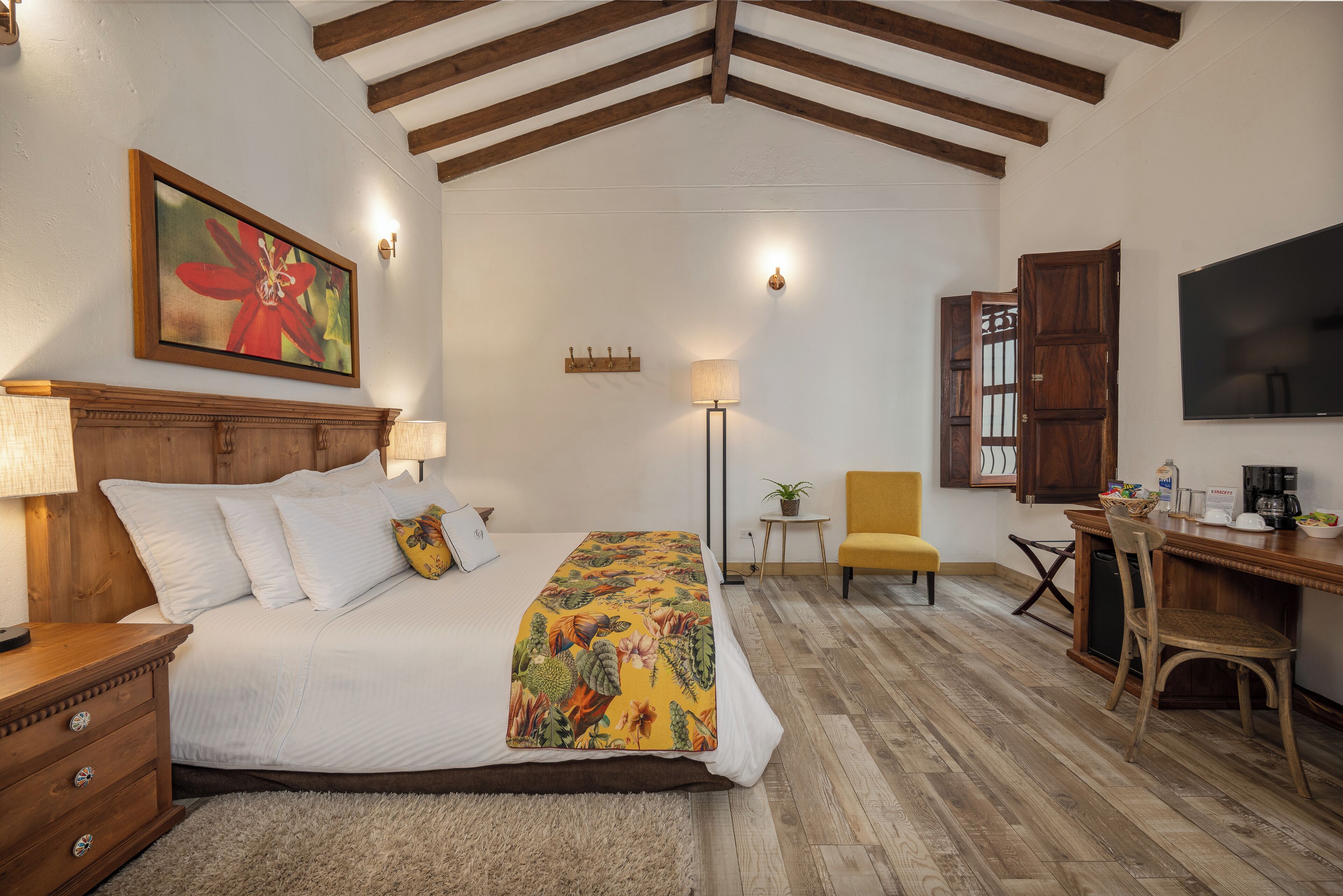 A bedroom with a bed, bedside table, lamp, and a painting on the wall.