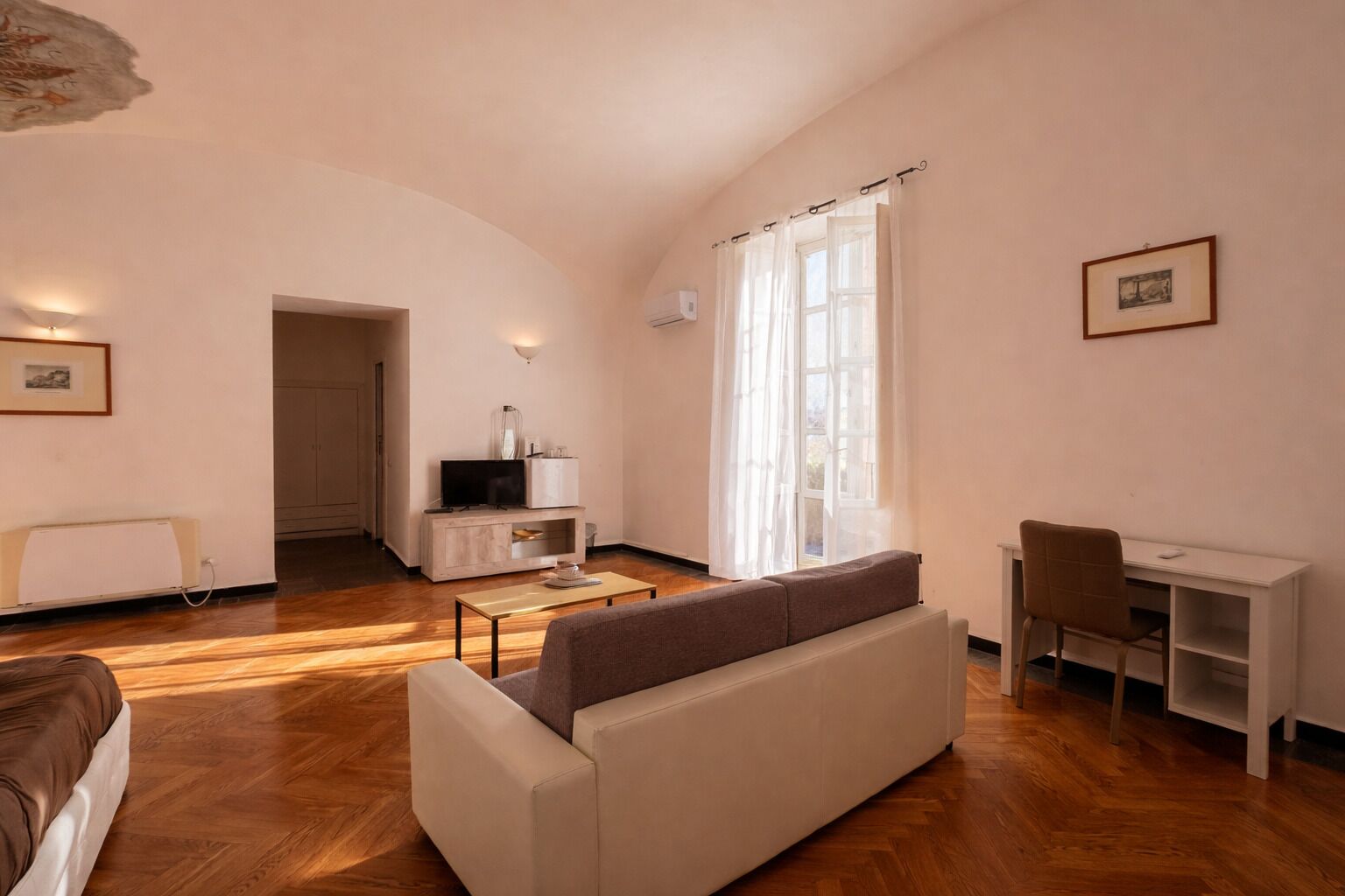 A living room with a sofa, a TV, a desk, and a chair.
