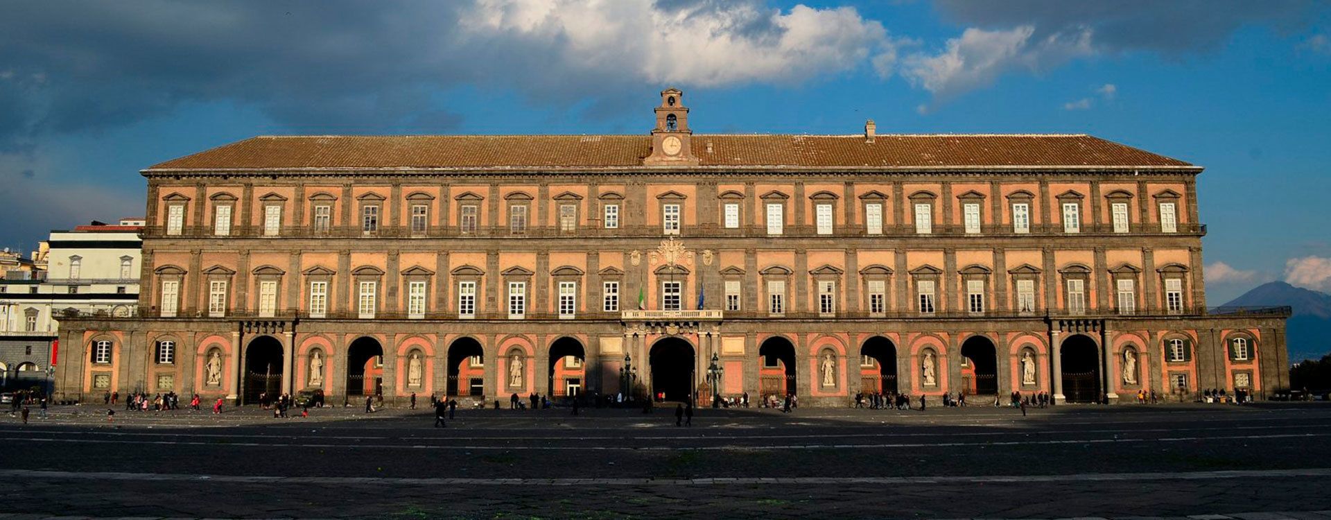 Um edifício grande e histórico, com várias arcadas e estátuas na frente.