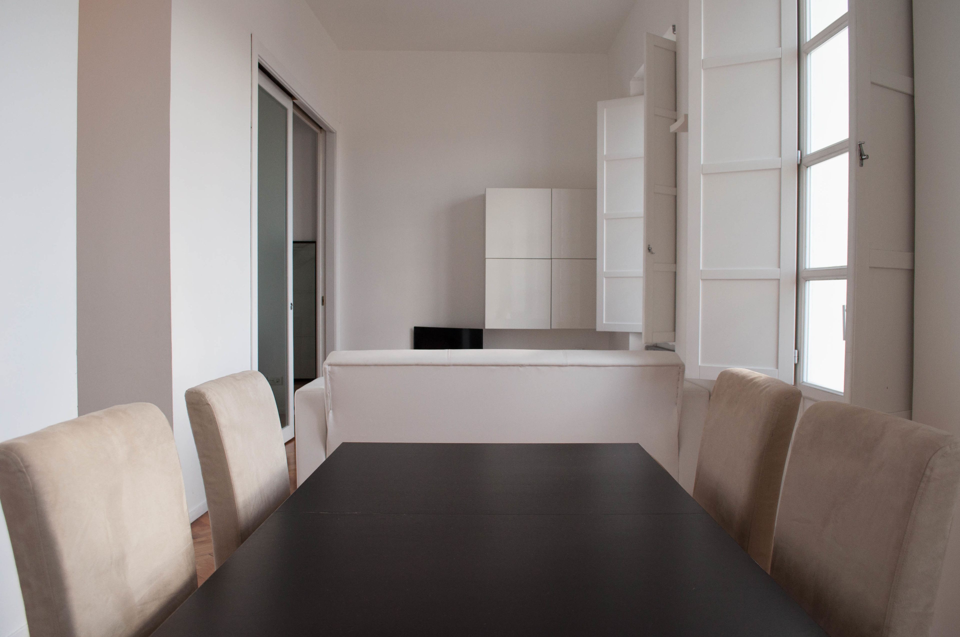 A conference room with a dark table, beige chairs, and a white cabinet in the background.
