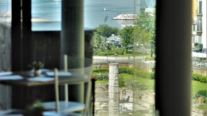 A restaurant with a view of a body of water and a distant cityscape. - Hotel Terme Neronensis (Pozzuoli)