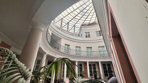 A multi-level atrium with a glass ceiling, columns, and potted plants. - Hotel Terme Neronensis (Pozzuoli)