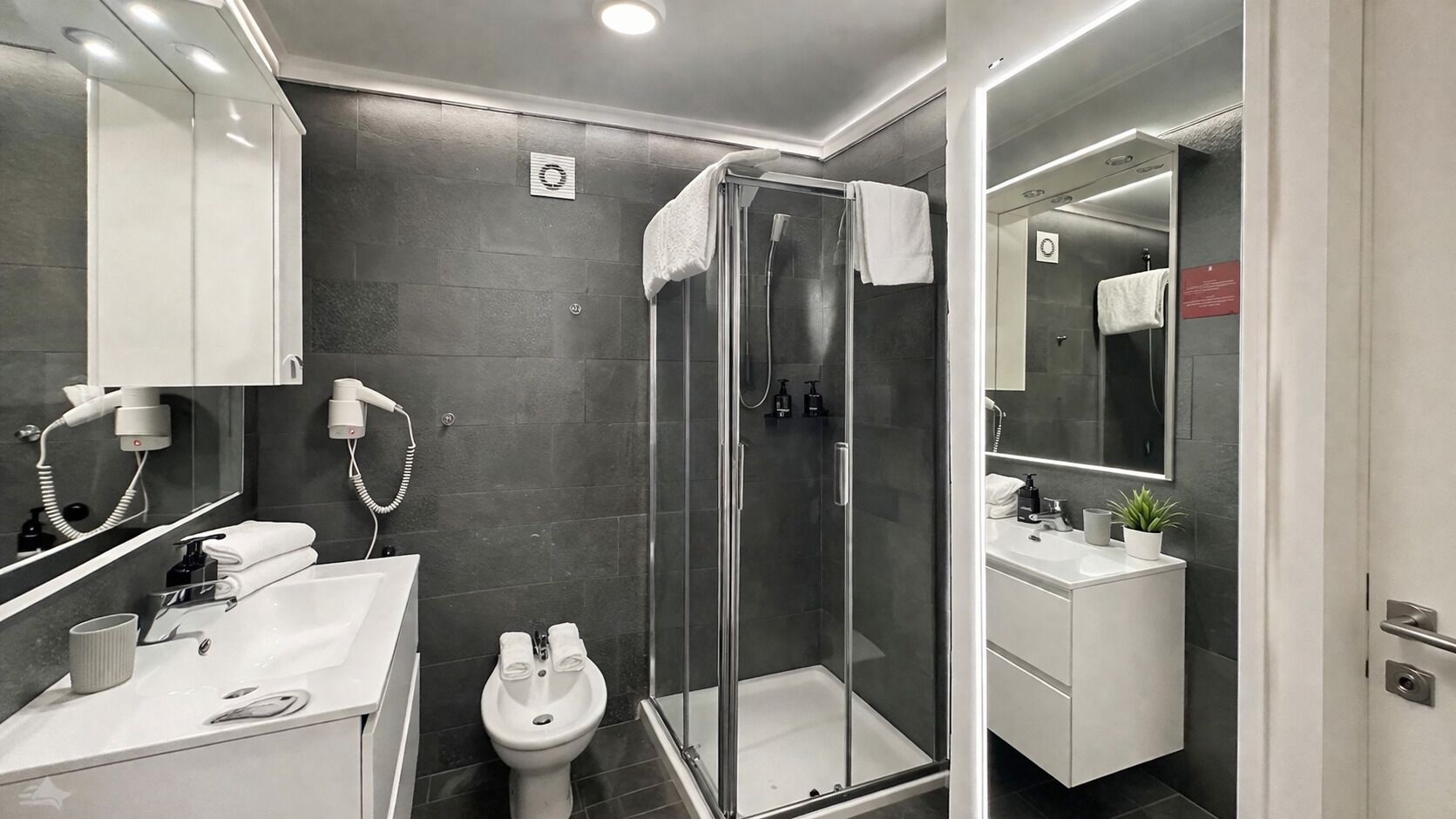 Une salle de bain moderne avec une douche à parois de verre, un lavabo, des toilettes et un meuble-lavabo avec un miroir.