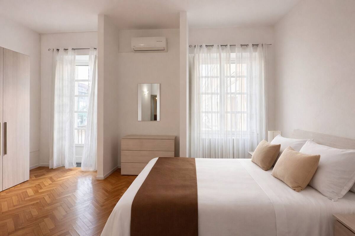 A bedroom with a bed, a dresser, a mirror, and an air conditioning unit.
