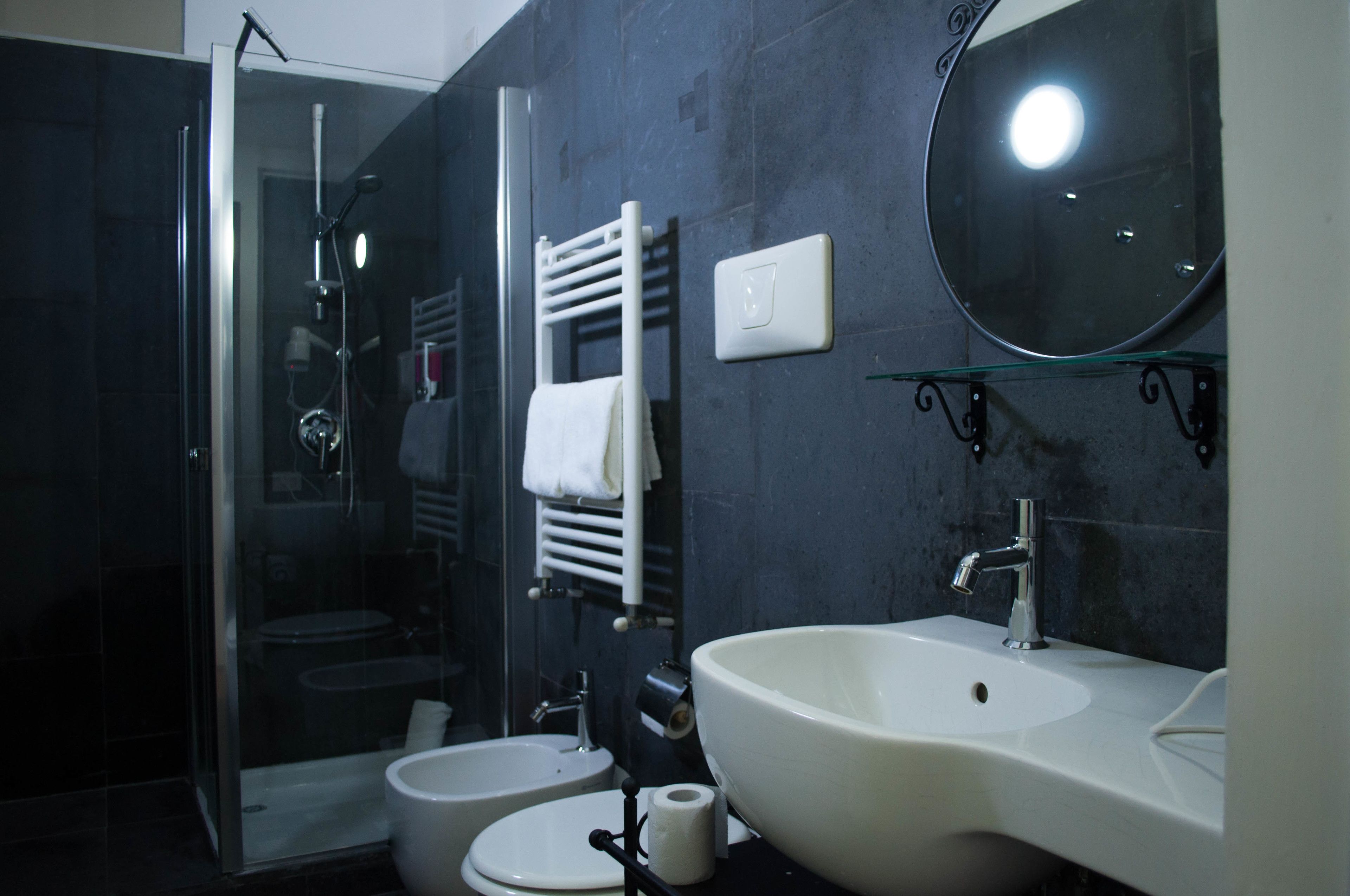 Une salle de bain moderne avec une douche à l’italienne en verre, un lavabo blanc et un grand miroir.