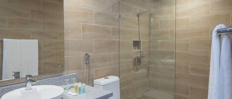 Un baño moderno con un lavamanos independiente, un inodoro y una ducha con cerramiento de vidrio.