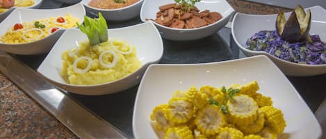 A buffet with various dishes including corn, mashed potatoes, and a salad.