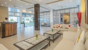 A spacious lobby with a reception desk, seating area, and a large pillar. - whala!urban punta cana (Punta Cana)