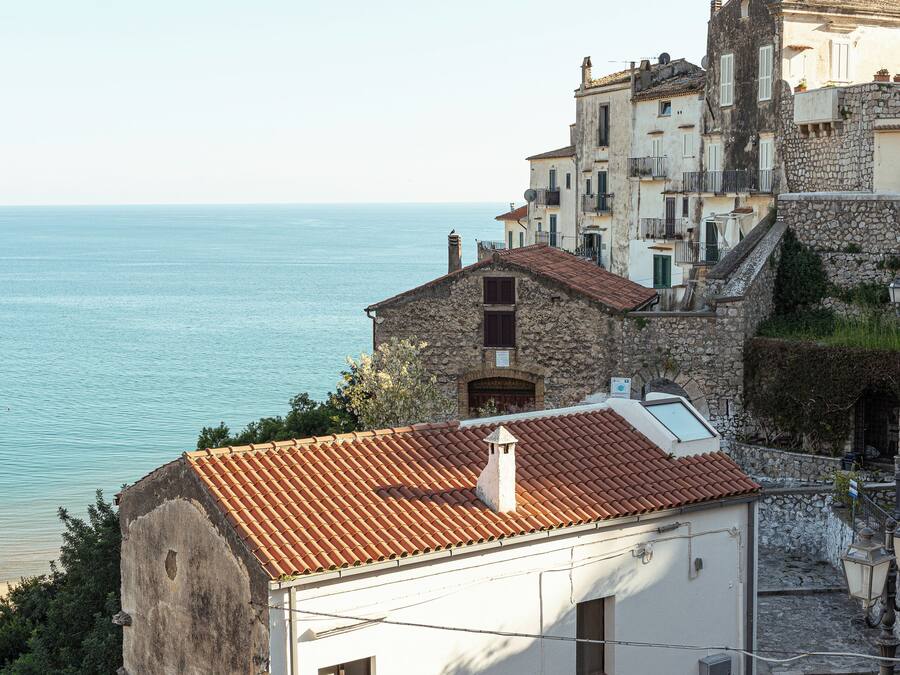 Un edificio costero con tejado de baldosas, paredes de piedra y vistas al mar.