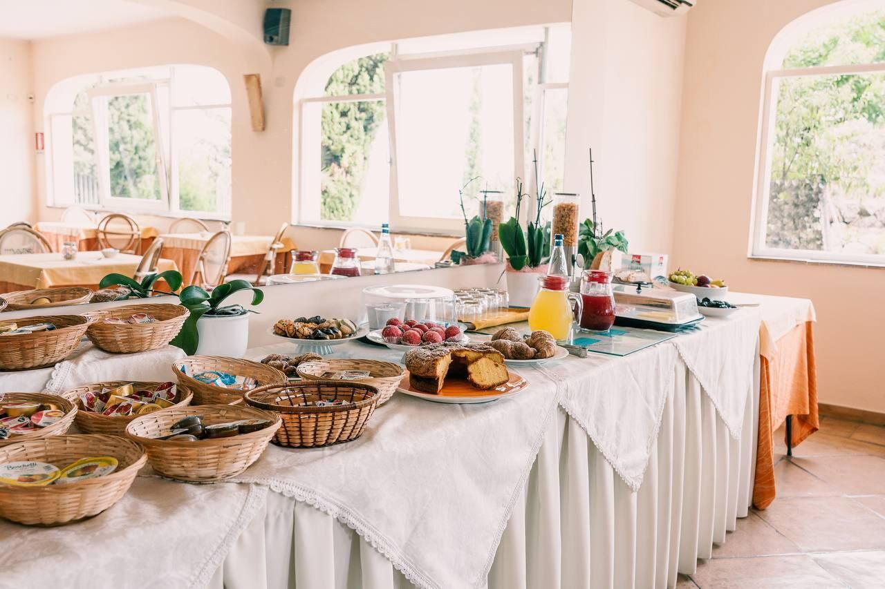 A buffet table with various food items and baskets, set in a room with large windows and a white tablecloth.