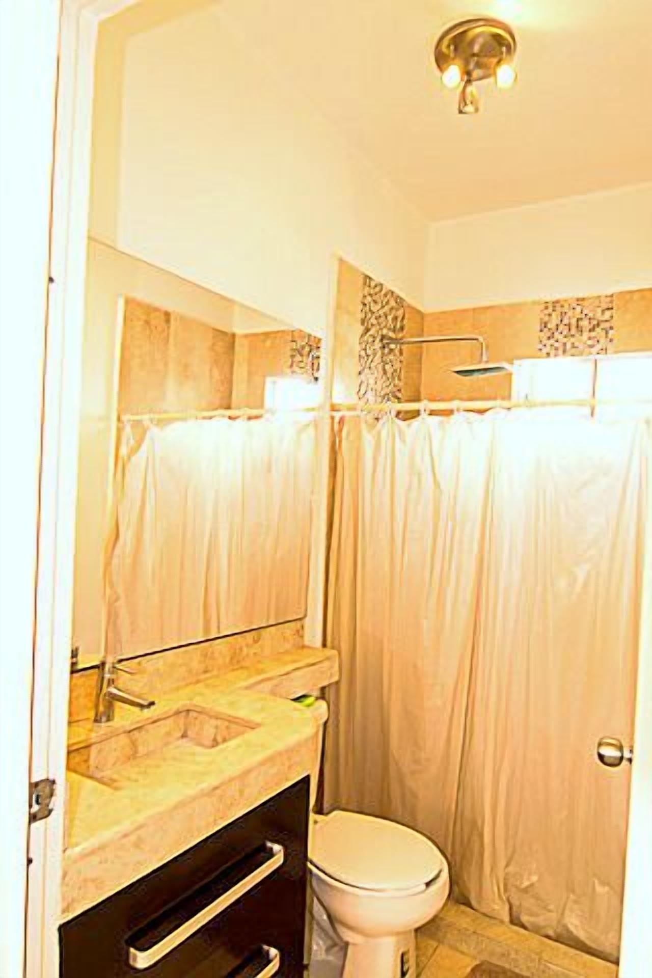 A bathroom with a shower curtain, a toilet, and a sink with a mirror above it.