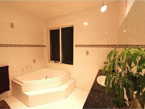 A bathroom with a bathtub, a sink, and a window.