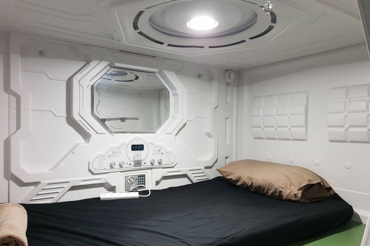 Een kamer met een bed, een bedieningspaneel, een spiegel en een groene vloer.