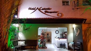 The entrance to Hotel Caldas with a Christmas tree and a bench outside.
