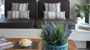 A living room with two sofas, a coffee table with a plant, and a wall-mounted air conditioner.