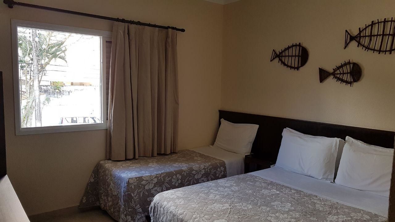 A hotel room with two beds, a window with curtains, and three wall-mounted fish decorations.