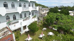 Un immeuble à plusieurs étages doté de balcons, une cour avec des espaces de détente en plein air et une végétation luxuriante.