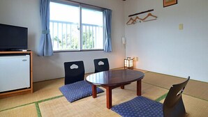 Une pièce avec un plafond en bois, une table à manger avec des chaises, un téléviseur et une fenêtre avec des rideaux.