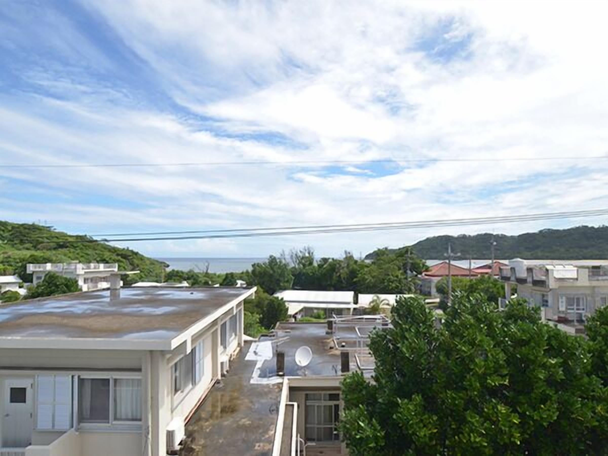 A residential area with houses, a clear sky, and a hilly landscape in the background.