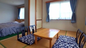 Une pièce de style japonais traditionnel, avec un sol recouvert de tatamis, une table en bois et un futon servant de lit.