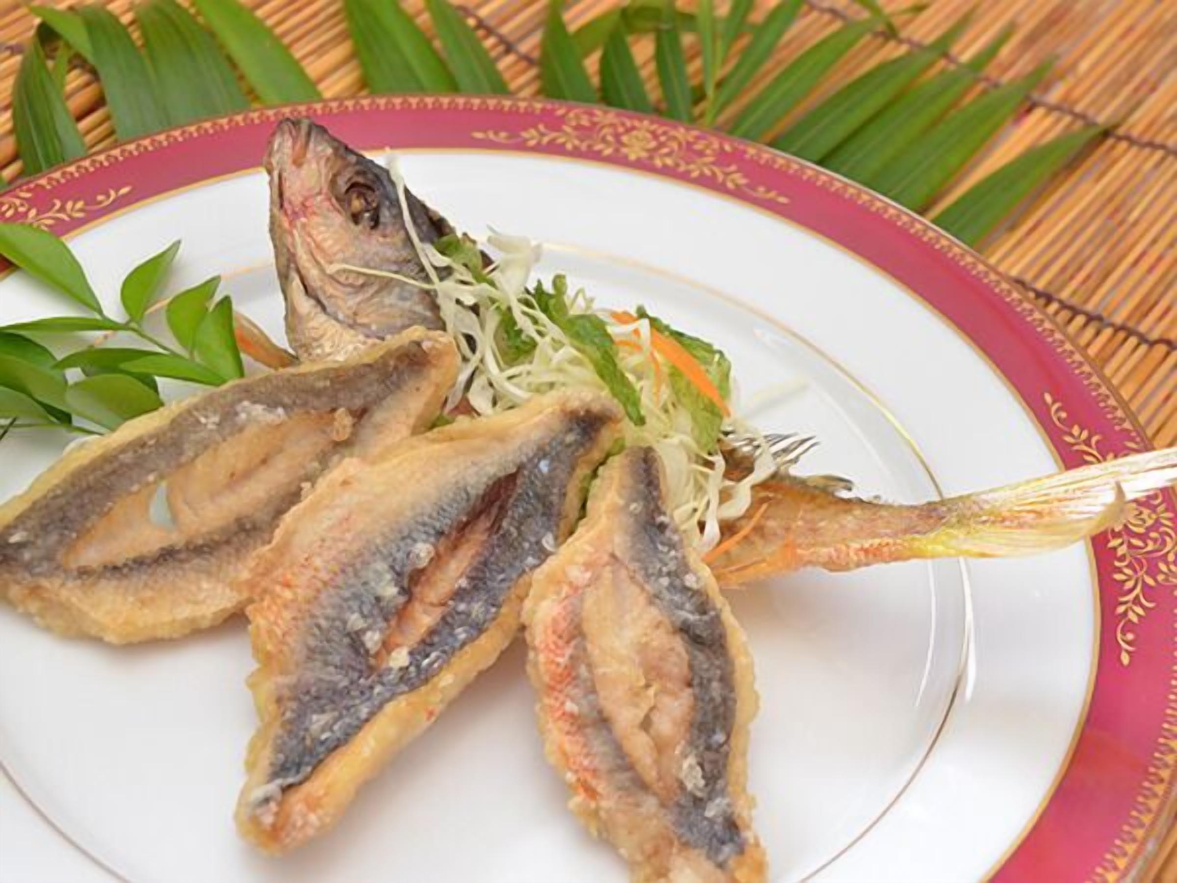 A plate with fried fish and a side of shredded vegetables.