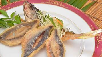A plate with fried fish and a side of shredded vegetables.