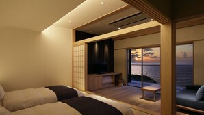 A modern hotel room with two beds, a TV, and a view of the sea at sunset. - Taiza Onsen Sumihei (Kyotango)