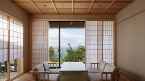 A traditional Japanese room with tatami flooring, a low table, and a sofa. - Taiza Onsen Sumihei (Kyotango)