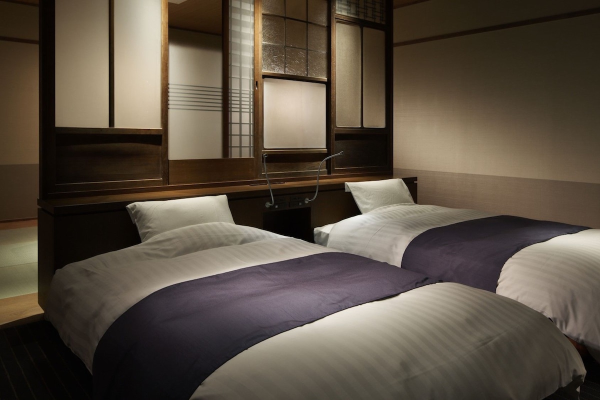 A hotel room with two beds, a wooden headboard, and a large mirror.