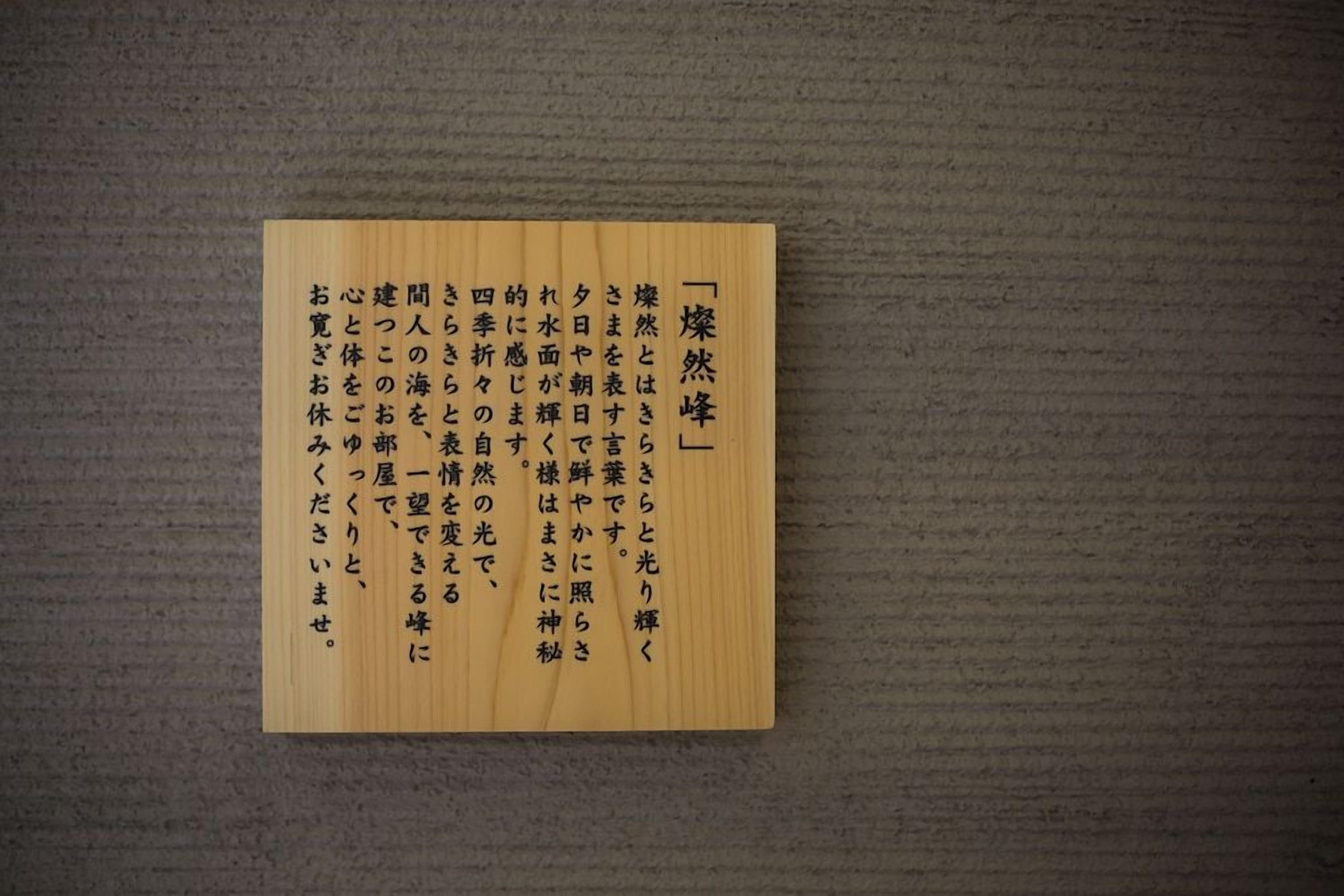 A wooden plaque with Japanese text on a textured wall.