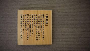 A wooden plaque with Japanese text on a textured wall.