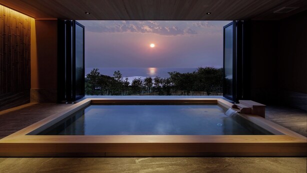 A modern indoor swimming pool with a view of the sunset over the ocean. - Taiza Onsen Sumihei (Kyotango)