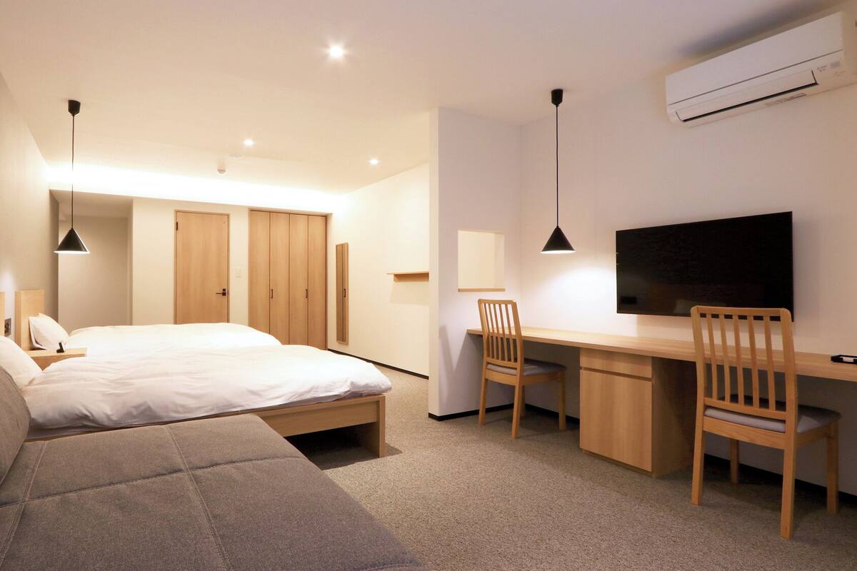 Une chambre d’hôtel moderne équipée d’un lit, d’un bureau, d’une chaise, d’une télévision et d’une armoire.