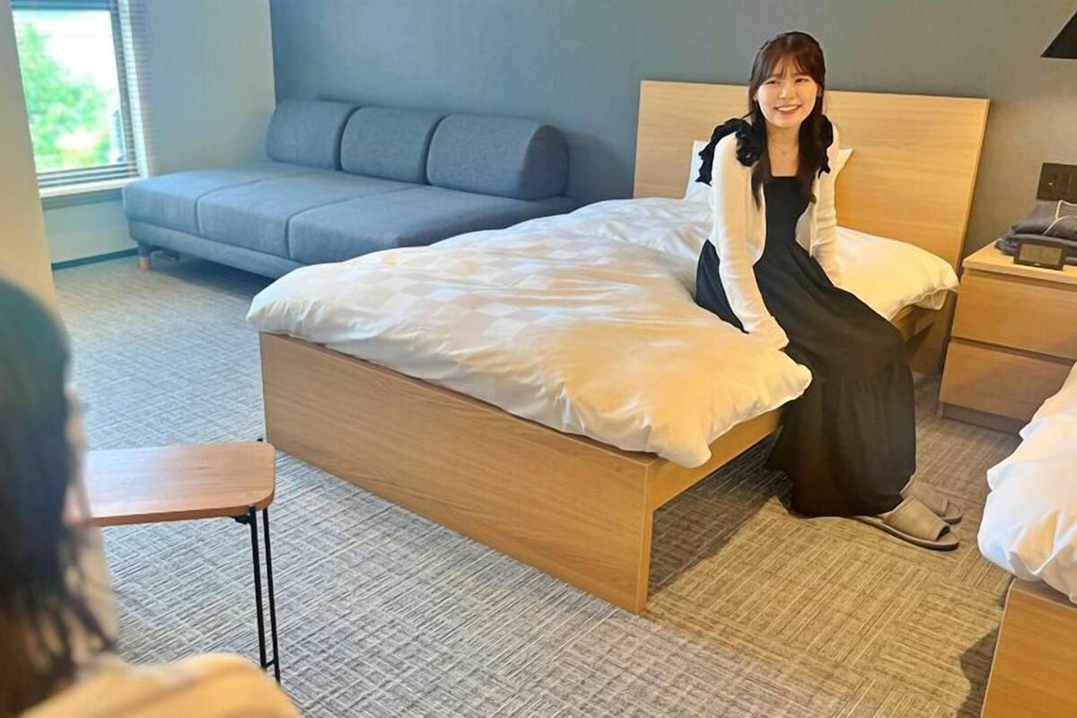 Une chambre d’hôtel avec un lit, une table de chevet, une commode, un canapé et une fenêtre.