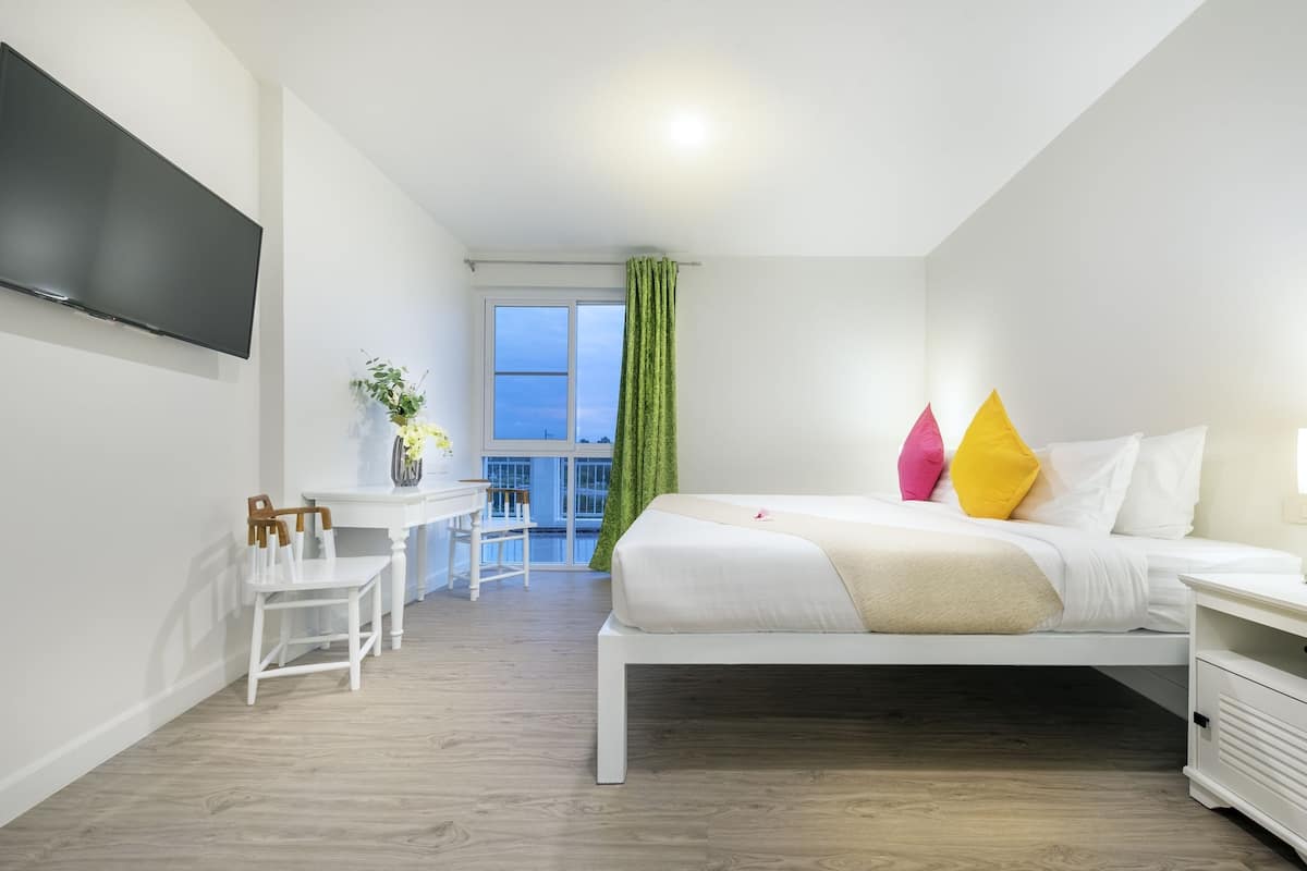 Quarto de hotel moderno com cama, escrivaninha e televisão.
