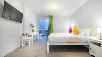 A modern hotel room with a bed, a desk, and a TV.