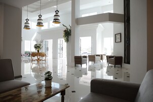 Una habitación amplia y bien iluminada, con piso pulido, muebles elegantes y ventanas grandes que dejan entrar luz natural.