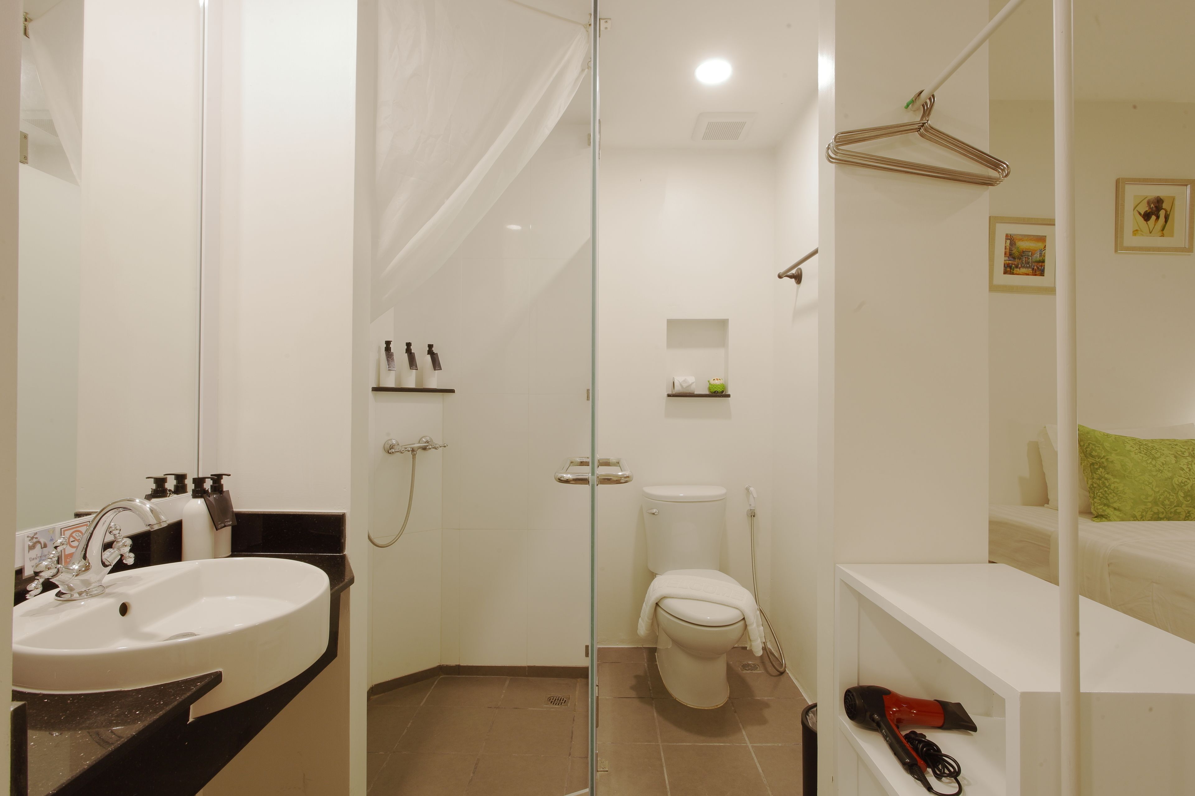 A bathroom with a sink, toilet, shower, and a mirror.
