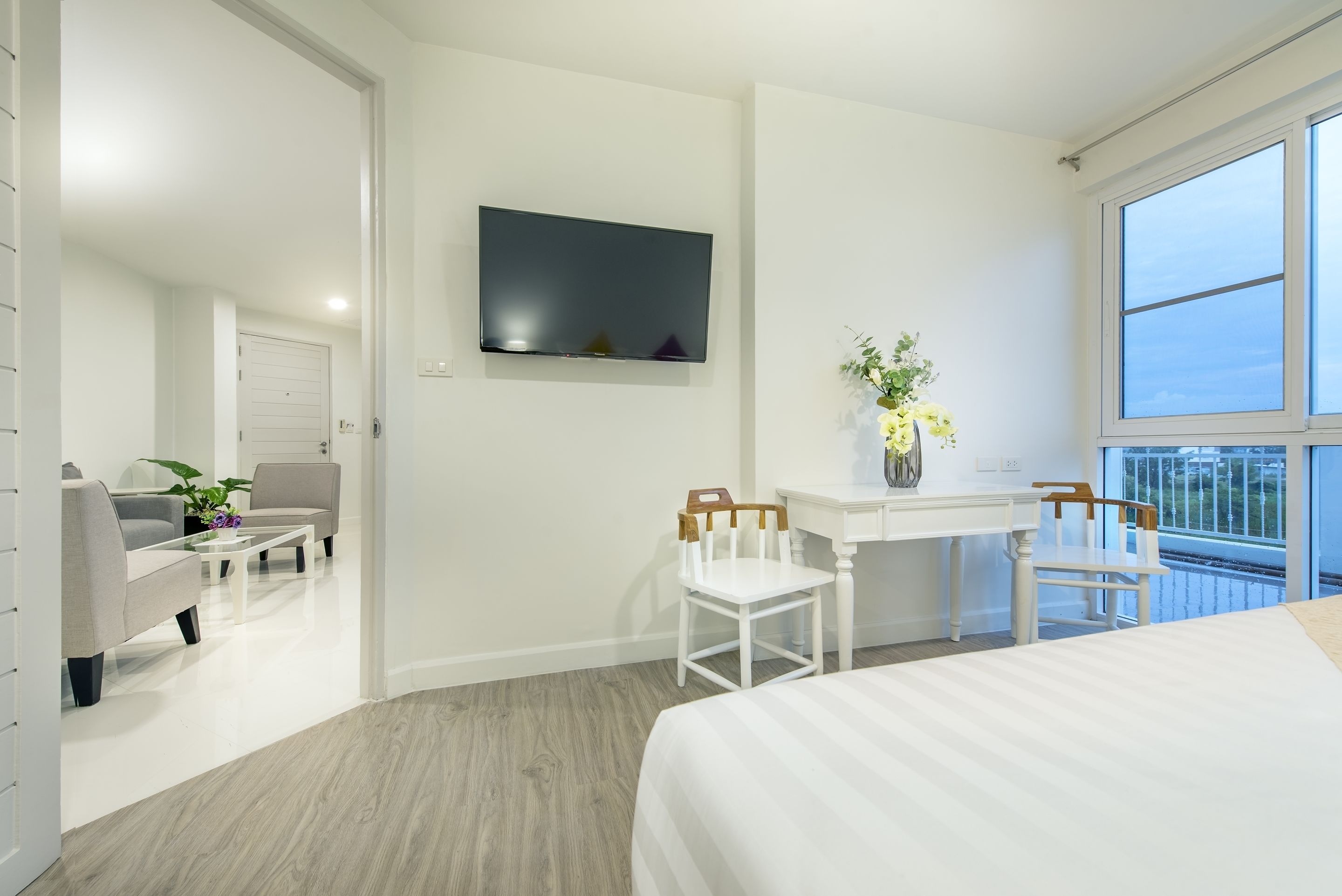 Ein modernes Hotelzimmer mit Bett, Schreibtisch mit Stuhl, Wandfernseher und Balkon mit Aussicht.